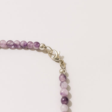 A close-up detail of 4mm amethyst round beads meeting professional-grade sterling silver hardware, showcasing the high-polish finish and secure closure.

