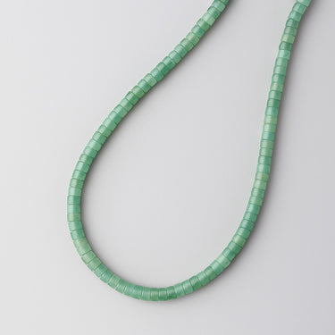 A macro close-up view highlighting the unique disc-shaped green aventurine beads and their natural soft green color variations.
