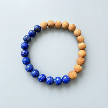 A top-down view of an 8mm Lapis Lazuli and Golden Sandalwood bead bracelet, highlighting the natural grain of the wood and the stone's rich color.
