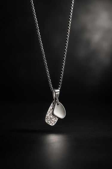 textured silver amulet and a smooth surface amulet necklace on box chain dramatic lighting masculine statement jewelry