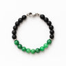 Bracelet with black and green beads on a white background