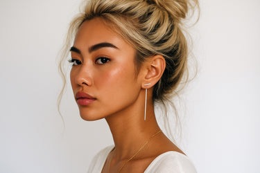 Close-up of a woman wearing sterling silver earrings with a plain background