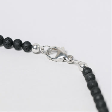Close-up of a black beaded necklace with a silver clasp on a white background