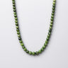 Green beaded necklace on a light gray background