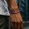 Hand wearing a purple bracelet with a blurred background