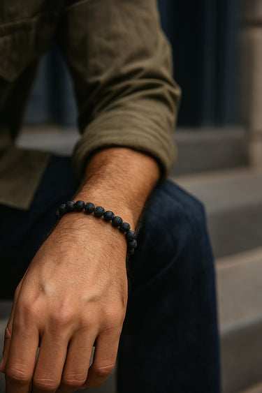 Person wearing a black beaded bracelet on a blurred background