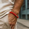 Person wearing a red beaded bracelet on a blurred background