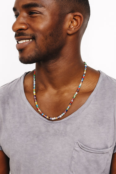 Man wearing a colorful beaded necklace against a neutral background