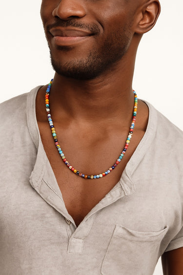 Man wearing a colorful beaded necklace with a neutral background
