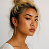 Woman with styled hair and earrings, minimal silver bar drop earrings with sleek vertical design for everyday wear against a plain background. 