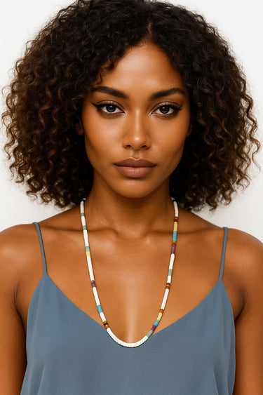Woman wearing a colorful beaded necklace against a plain background