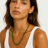 Woman wearing a green beaded necklace against a white background