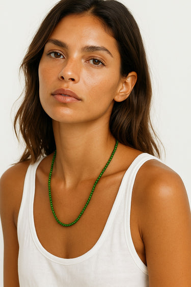 Woman wearing a green beaded necklace against a white background