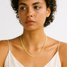Woman wearing a gold necklace against a white background