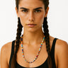 Woman with braided hair wearing a colorful beaded necklace against a white background