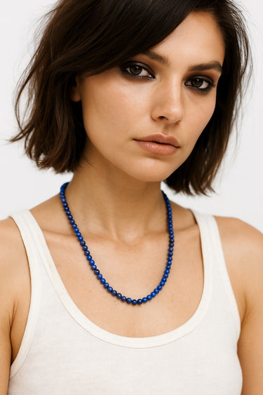 Woman wearing a blue beaded necklace against a plain background