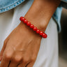 Hand wearing a red beaded bracelet with a blurred background