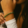 Close-up of a woman wearing a 4mm green jade bracelet with one sterling silver accent with a blurred background