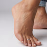 Close-up of a foot with a sterling silver overlap style toe ring on the third toe on a neutral background.