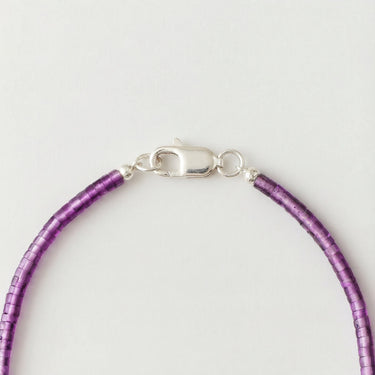 A close-up view of purple amethyst heishi beads finished with a high-polish silver lobster clasp.
