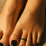 Close-up of feet with black nail polish on a neutral background