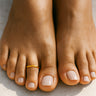 Bright gold anodized aluminum toe ring on toes — smooth rounded fit, COLORS Collection by Clay & Chloe Jewelry.