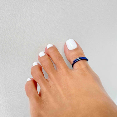 Angled view of dark blue anodized aluminum toe ring — smooth finish and comfortable everyday fit.