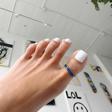 Side angle of dark blue anodized aluminum toe ring on big toe — lightweight water-friendly design.