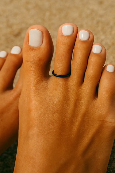 Side angle of dark blue anodized aluminum toe ring on big toe — lightweight and water-friendly design.