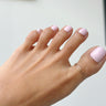 woman’s cute foot up in the air wearing a gold overlap big toe ring in 14k gold-filled.