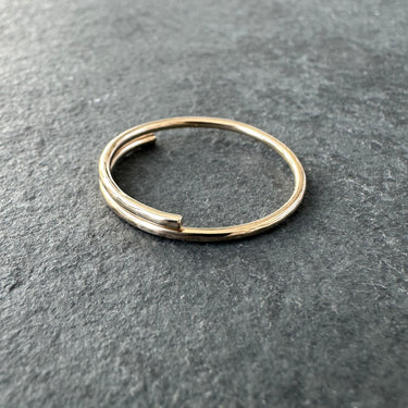 Gold overlap big toe ring on a dark gray surface - side view