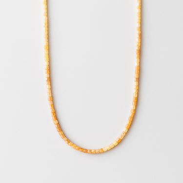 A strand of 2mm golden orange faceted sunstone cube beads displayed in a U-shape against a bright white background.

