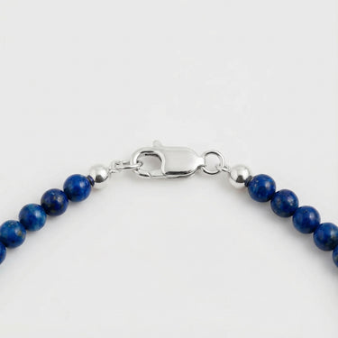 A macro close-up of 4mm blue gemstone beads finished with a high-polish silver lobster clasp.
