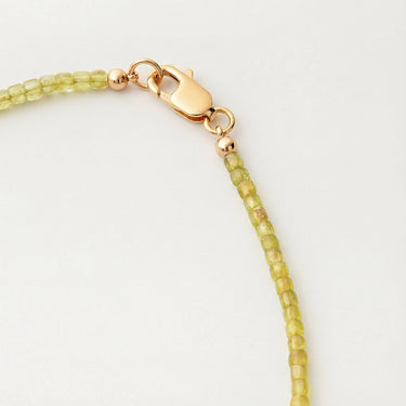 Close-up of a men’s necklace with 2-3mm faceted cube peridot beads and a polished 14K gold-filled lobster clasp.