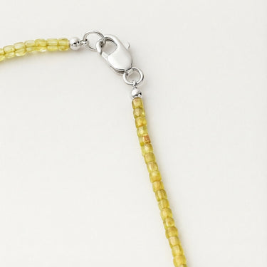 Close-up of a men’s necklace with 2-3mm faceted cube peridot beads and a polished sterling silver lobster clasp.