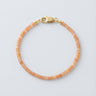 A 2mm faceted Golden Sunstone cube bead bracelet featuring warm honey tones and a high-polish gold lobster clasp, displayed against a light grey background.
