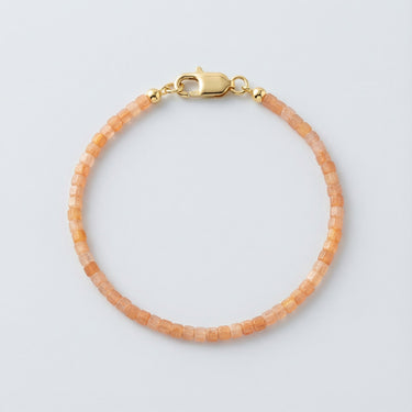 A 2mm faceted Golden Sunstone cube bead bracelet featuring warm honey tones and a high-polish gold lobster clasp, displayed against a light grey background.
