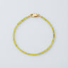 A 2mm faceted Peridot cube bead bracelet featuring vibrant lime-green tones and a high-polish gold lobster clasp.
