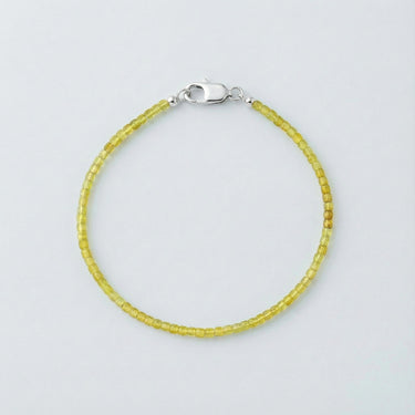 A 2mm faceted Peridot cube bead bracelet with a high-polish silver lobster clasp, highlighting the light-reflecting geometric facets.
