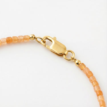 Close-up of a men’s necklace with 2mm faceted sunstone beads and a polished 14K gold-filled lobster clasp.