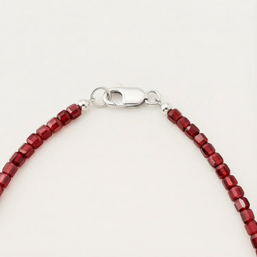 Close-up of a men’s necklace with 3mm faceted red garnet beads and a polished sterling silver lobster clasp.