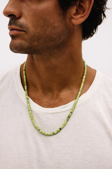 Side view of a model wearing a 4mm African green chrysoprase heshi necklace, styled with a white t-shirt.
