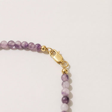 Close-up of a men’s necklace with 4mm purple amethyst beads and a polished 14K gold-filled lobster clasp.