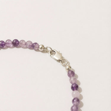 Close-up of a men’s necklace with 4mm purple amethyst beads and a polished sterling silver lobster clasp.