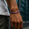 A close-up of a male model's wrist showcasing the rich purple tones and low-profile fit of a 4mm Amethyst heishi bead bracelet.
