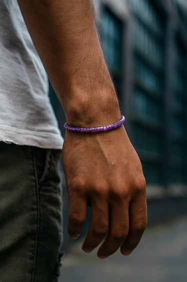 A close-up of a male model's wrist showcasing the rich purple tones and low-profile fit of a 4mm Amethyst heishi bead bracelet.
