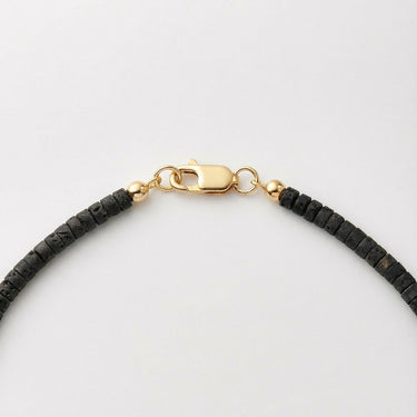 Close-up of a men’s necklace with 4mm black lava heshi beads and a polished 14K gold-filled lobster clasp.