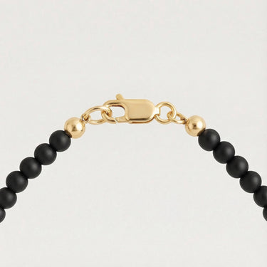 Close-up of a men’s necklace with 4mm black onyx beads and a polished 14K gold-filled lobster clasp.