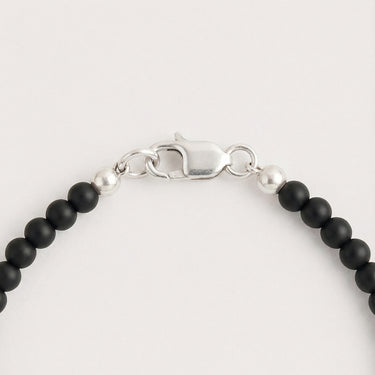 Close-up of a men’s necklace with 4mm black onyx beads and a polished sterling silver lobster clasp.