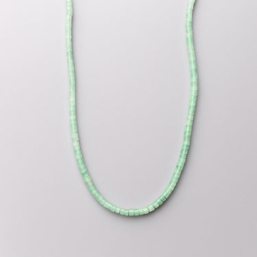 A single strand of 4mm mint green aventurine heishi beads displayed in a U-shape against a neutral light grey background.
